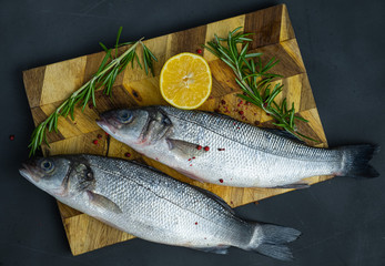 fresh sea bass fish on a wooden board, two fish