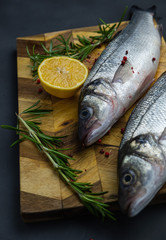 fresh sea bass with lemon and rosemary on a wooden board