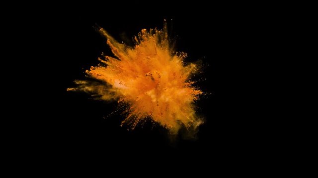 Colored orange powder explosion, abstract close up dust isolated on black background in slow motion