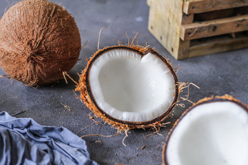 Obraz na płótnie Canvas Photo of fresh coconut on a table. Tropical palm fruits. Coconut cut in half. Beach fruit. Retro dark background. Rustic wooden board. Front view. Image