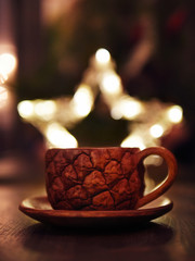 Custom made pineapple brown clay coffee cup on wooden table in cafe with bokeh light background