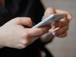 Detail of female hands texting mobile phone pointing finger on smartphone screen blurred background indoors