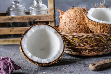 Photo of fresh coconut on a table. Tropical palm fruits. Coconut cut in half. Beach fruit. Retro dark background. Rustic wooden board. Front view. Image