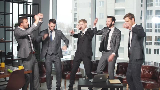 Dancing happy business men after meeting in office, enjoy work together, celebrating at work. panoramic window in the background