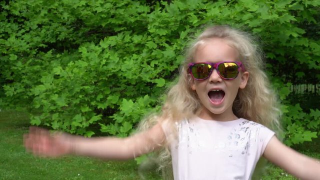 Happy blond girl put sun glasses on. Pretty little lady at park, Gimbal motion.
