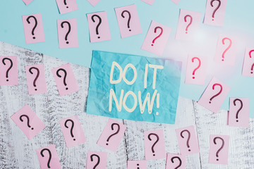 Handwriting text writing Do It Now. Conceptual photo not hesitate and start working or doing stuff right away Scribbled and crumbling papers with thick cardboard above wooden table