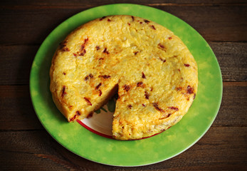 Potato and sausage omelette on plate on wood
