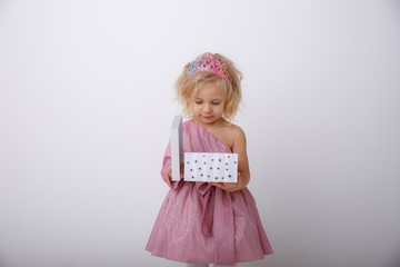 cute little girl in a princess dress with a crown holding a gift on a white background