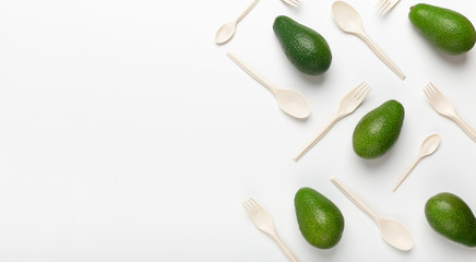 Creative composition of avocados and eco plastic spoons