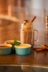 A glass jar of coffee millkshake with cinnamon sticks
