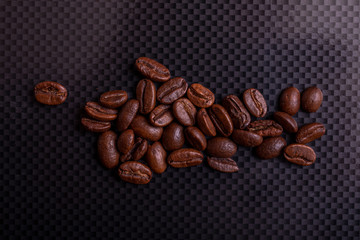 Roasted brown coffee beans on black carbon table or dark background.