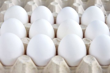 Row of white chicken eggs in cardboard container. healthy protein breakfast. Fresh organic chicken eggs with selective focus. Egg box. Easter preparation. Raw eggs for Easter holiday. Uncooked 