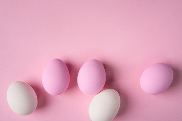 Easter eggs scattered on pink background with copy space above