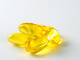 Omega 3 fish oil capsules isolated on white background. Golden color capsules - vitamin E, D or multivitamin.