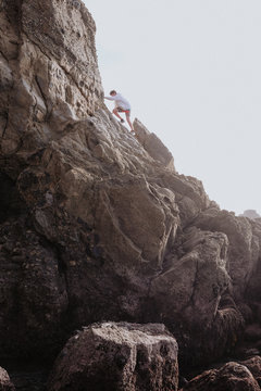 Boy climbing rocks on each, Dana Point, California, USA