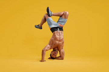Muscular young bodybuilder performing handstand stunt