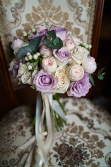 Brides wedding bouquet on the arm chair. wedding decoration, Wedding bouquets of purple and white flowers with greenery, decorated with silk ribbons, lie on wooden chairs.The bride's bouquet. Vertical