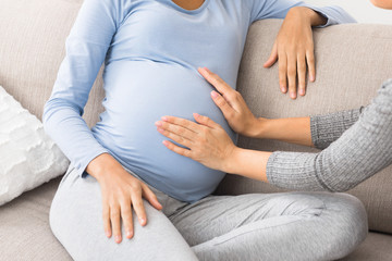 Woman visit pregnant friend and touching belly