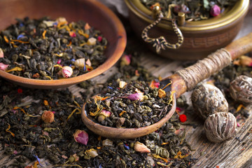 Dry tea leaves on a table in a composition with accessories for tea drinking