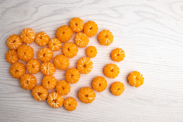 Heart made from peeled tangerines on a light wooden background with place for your text.