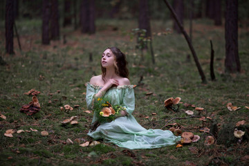 a beautiful girl in a green dress walks in the forest with a bouquet
