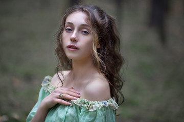 a beautiful girl in a green dress walks in the forest with a bouquet