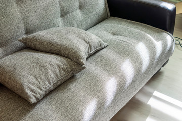 Gray sofa with pillows in sunny room
