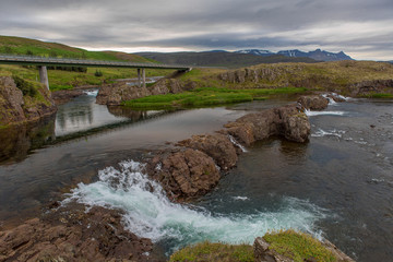 Panoramic view of a mountain river through which a long concrete bridge is thrown