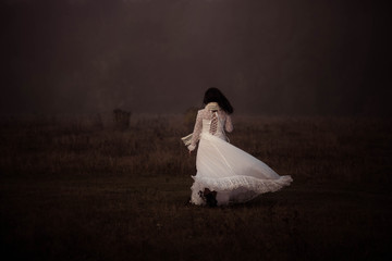 girl in a white dress on a mist field with oaks