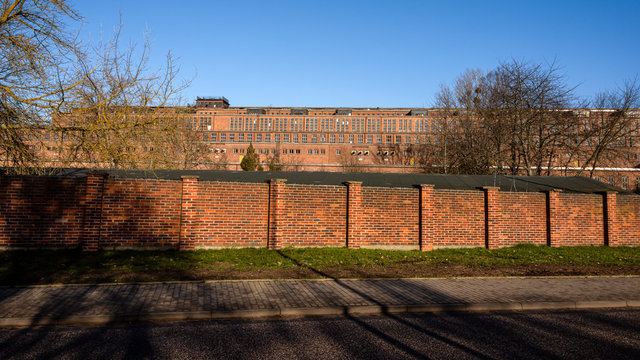 Germany, Saxony-Anhalt, Vockerode: Street view of big old defunct shut down former Vockerode lignite power plant building with brick stone facade, no chimneys and blue sky - concept energy lost place