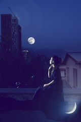 High Priestess tarot arcana concept woman sitting on rooftop looking at the Moon