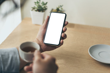 Mockup image blank white screen cell phone.man hand holding texting using mobile on desk at coffee shop.background empty space for advertise text.people contact marketing business,technology 