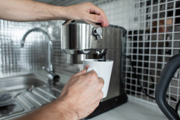 Guy prepare delicious aromatic coffee in a coffee machine. A simple way to make coffee