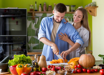 Boyfriend cutting healthy pumpkin for preparing vegan soup or pie