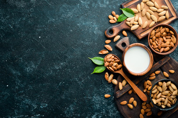 Almond milk and almonds on black stone background. Top view. Free space for your text.
