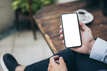 Mockup image blank white screen cell phone.man hand holding texting using mobile on desk at coffee shop.background empty space for advertise text.people contact marketing business,technology 