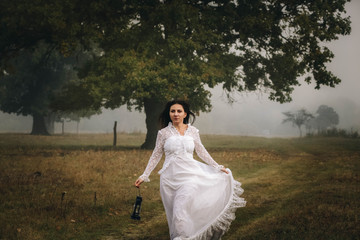 girl in a white dress on a mist field with oaks