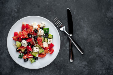 Greek salad in a white plate on a stone background