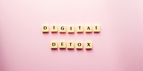 Digital detox text in tiles. Flat lay concept of tech escape on pink background