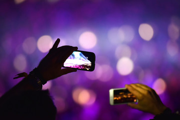 Hand holding smart phone and recording concert
