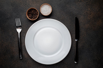 white plate with spices with  fork and knife on a stone background