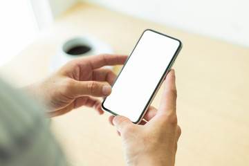 Mockup image blank white screen cell phone.man hand holding texting using mobile on desk at coffee shop.background empty space for advertise text.people contact marketing business,technology 