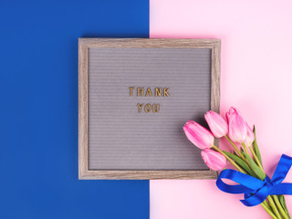 Thank you text composed on wooden board with letters on colorful classic blue and pink background....