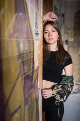 Young girl with challenging attitude looking at camera in an abandoned building. Casual military...