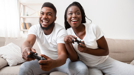 Joyful afro couple competing with each other in video game