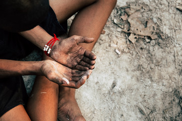 poor child or beggar begging you for help sitting at dirty slum. concept for poverty or hunger...