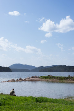Rear view of a man sitting by Shiroka Polyana lake, Rhodope Mountains, Bulgaria