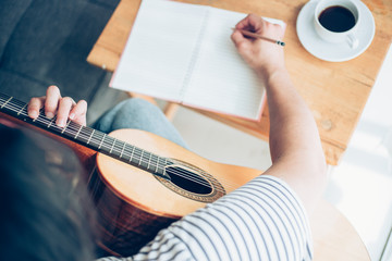 Fototapeta premium artist songwriter thinking writing notes,lyrics in book at studio.man playing live acoustic guitar relax chill.concept for musician creative.composer work process.people relaxing time with instrument