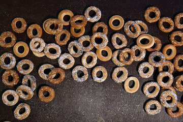 Bublik cookies pattern. Ring shaped roll cookies with different glaze on dark background..