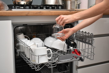 Open dishwasher with clean dishes in the white kitchen
